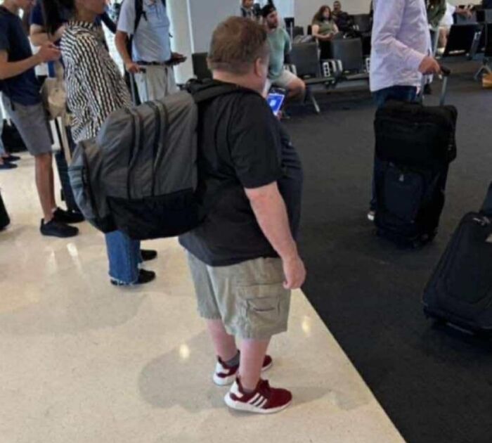 Man at airport wearing an extremely oversized backpack, an out of context image from pleasures of the occult collection.