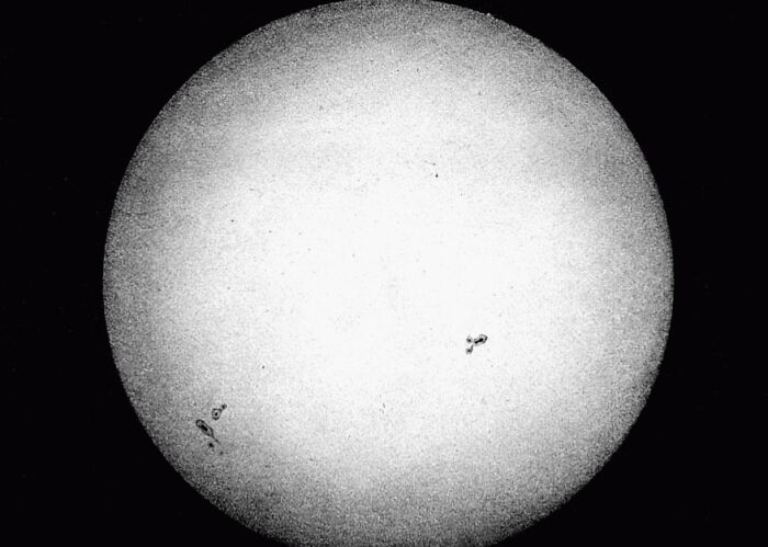 Black and white vintage photo showing early photography capturing the sun with visible sunspots and grainy texture.