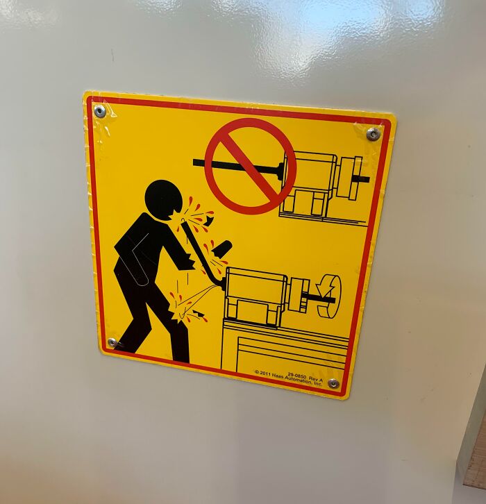 Warning sign showing workplace hazard with machinery causing injury, illustrating jobs that should pay more based on unsettling photos.