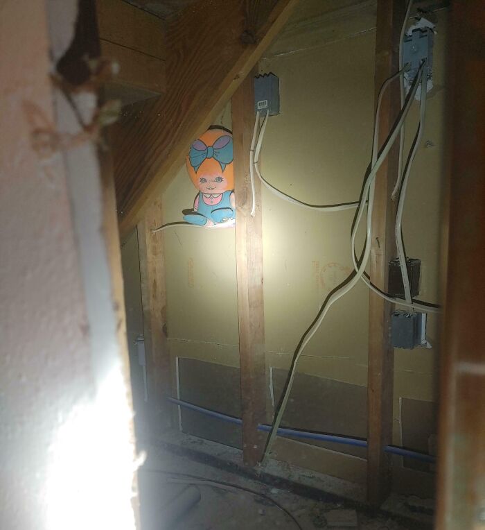Unsettling photo of a creepy doll face in the wall framing taken by workers, highlighting jobs that should pay more.
