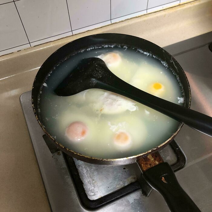 Pan with cloudy, unappetizing starchy water and broken eggs cooking on a stove seen in cursed and disgusting food pictures.