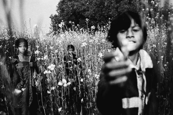 Black-and-white photo of children in a field capturing candid moments on the streets of India.