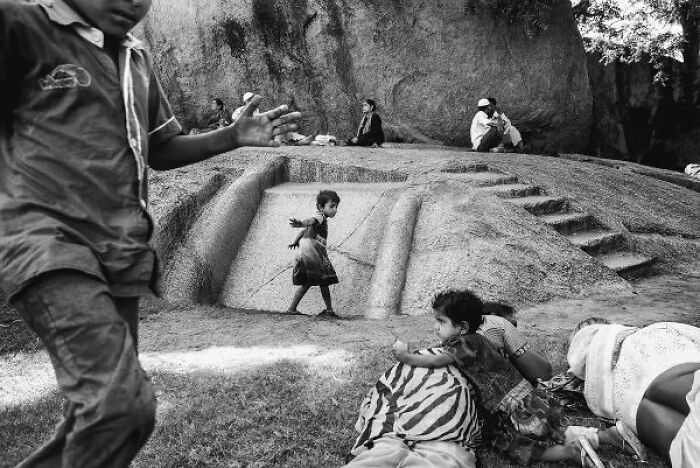 Black-and-white photo capturing children playing and resting on the streets of India with textured stone steps in the background.