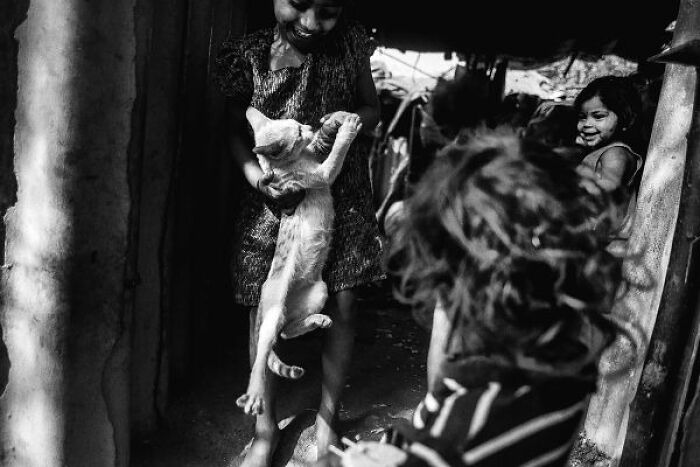 Children playing with a cat in a black-and-white photo capturing the streets of India and everyday joyful moments.