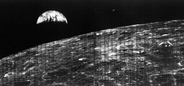 Black and white vintage photo of the moon's surface with Earth rising in the background, early photography example.