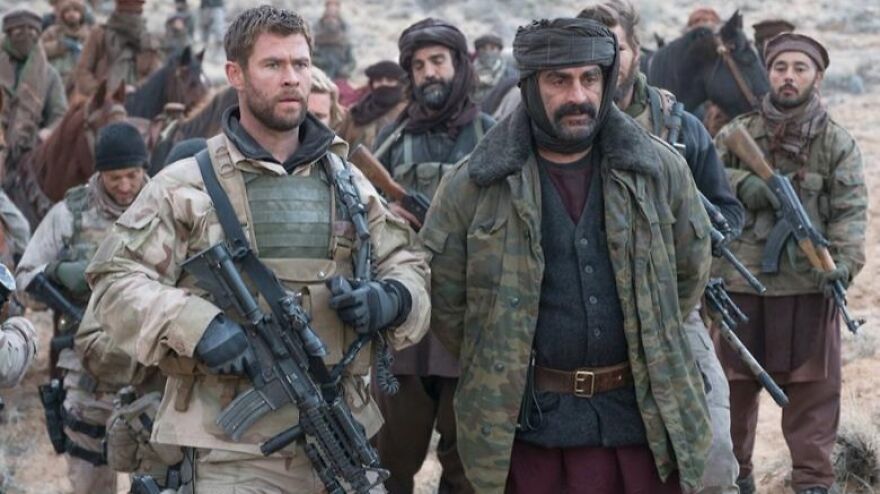 Soldiers and militants in desert gear during a tense moment, illustrating movies based on true stories.