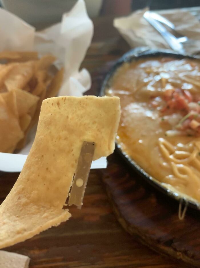 Close-up of a chip with a razor blade lodged inside, an example of Halloween fails impacting safety during the spooky season.