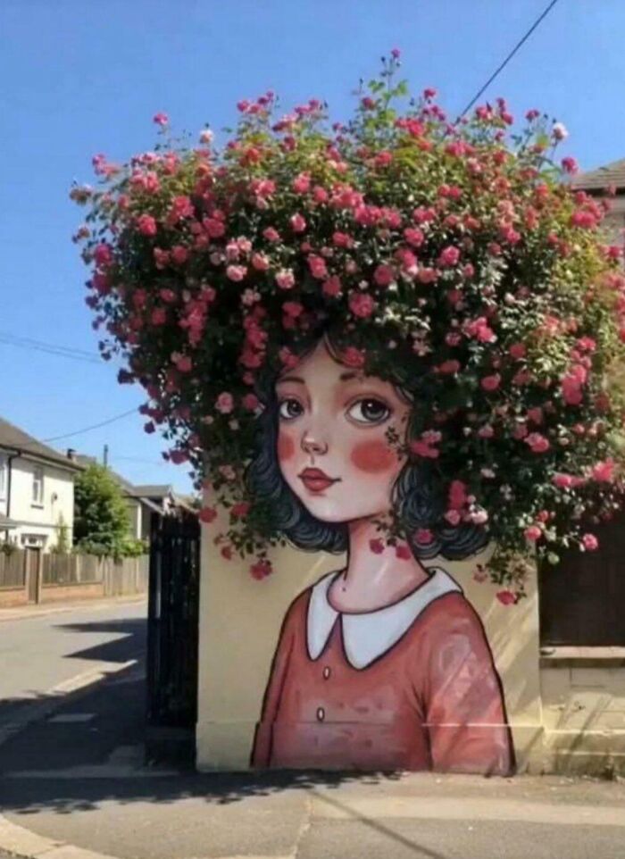 Street art mural of a girl with flowers blending as hair, showcasing powerful and beautiful street art in an urban setting.