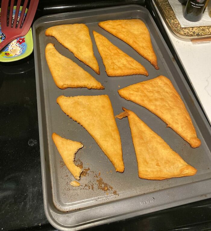 Baked triangular food pieces on a tray, appearing unusual and unappetizing in cursed and disgusting food pictures.