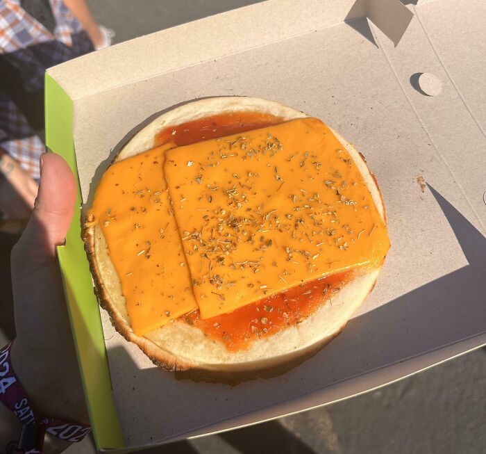 Partially assembled sandwich with slices of cheese and ketchup spread, a cursed and disgusting food picture.