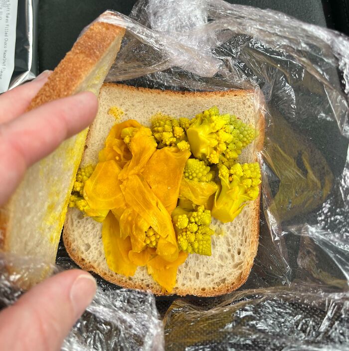 Close-up of a sandwich with unusual, yellowish-green spoiled vegetables, showcasing cursed and disgusting food imagery.