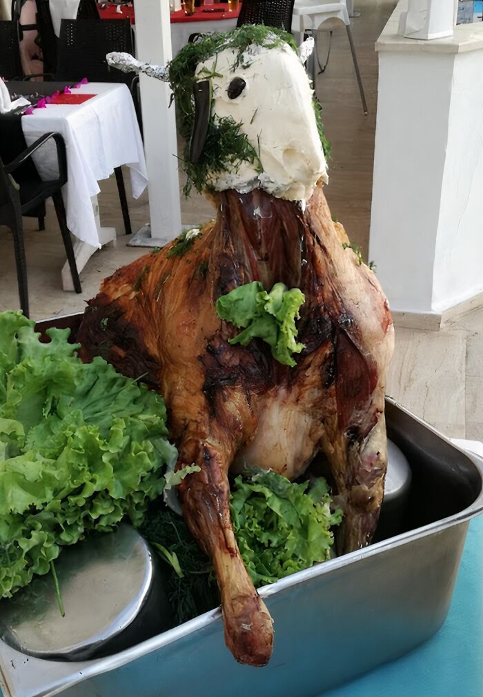 Roasted lamb with a head decorated in herbs and lettuce, an example of cursed and disgusting food presentation.
