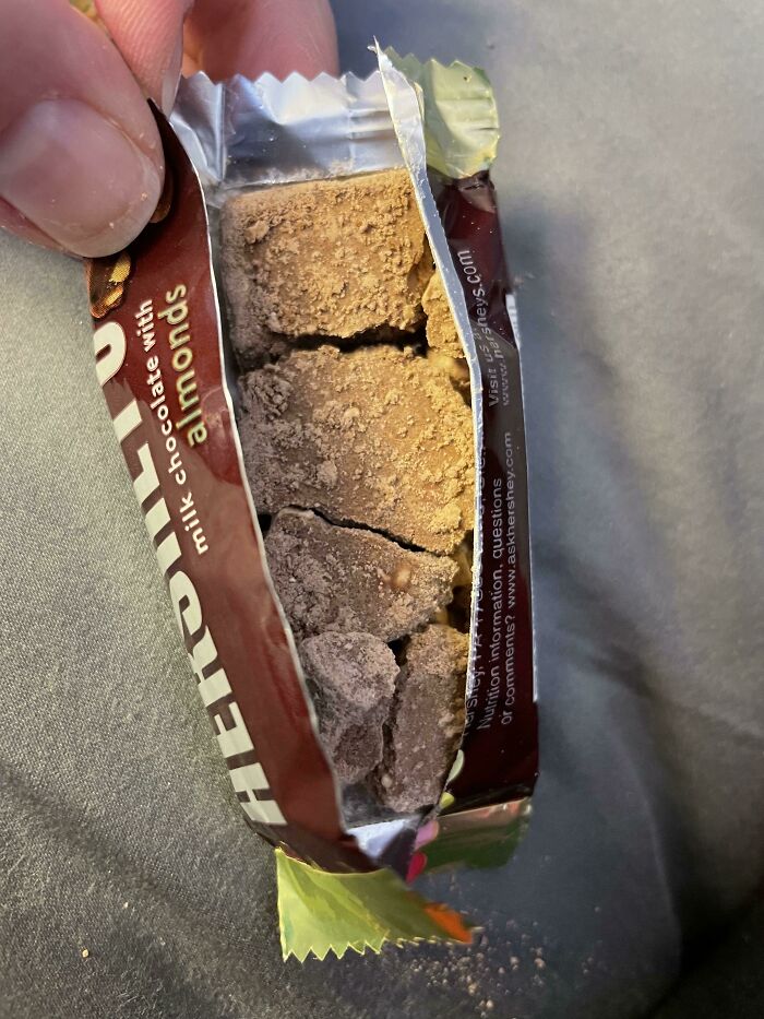 Broken milk chocolate with almonds in damaged packaging, an example of Halloween fails disappointing the holiday treats experience.