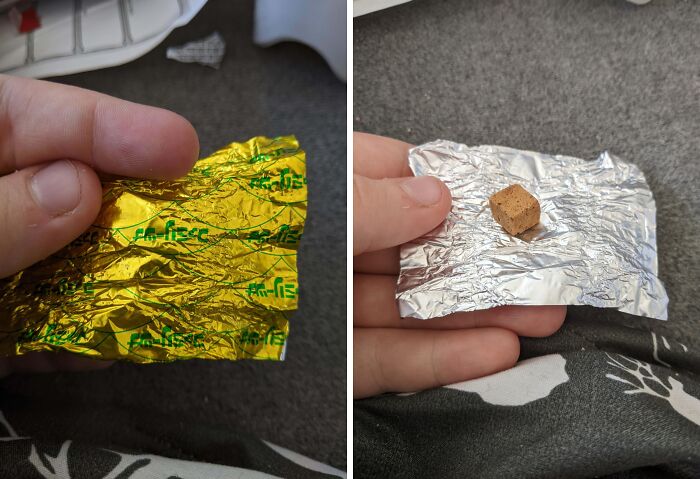 Hand holding small Halloween candy fail wrapped in foil, showing tiny treat on grey carpet background.