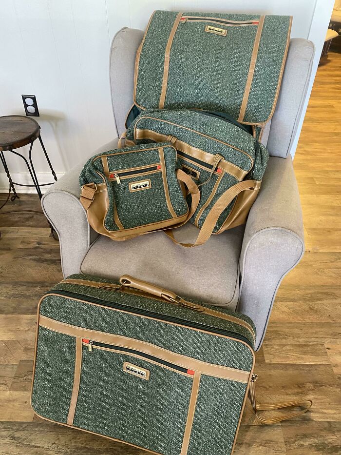 Vintage green and tan luggage set arranged on a chair and floor, showcasing thrift store jackpot finds by lucky shoppers.