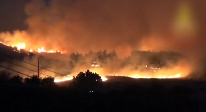 Wildfire blazing through a forest at night, illustrating extreme weather records and the power of our planet’s climate.