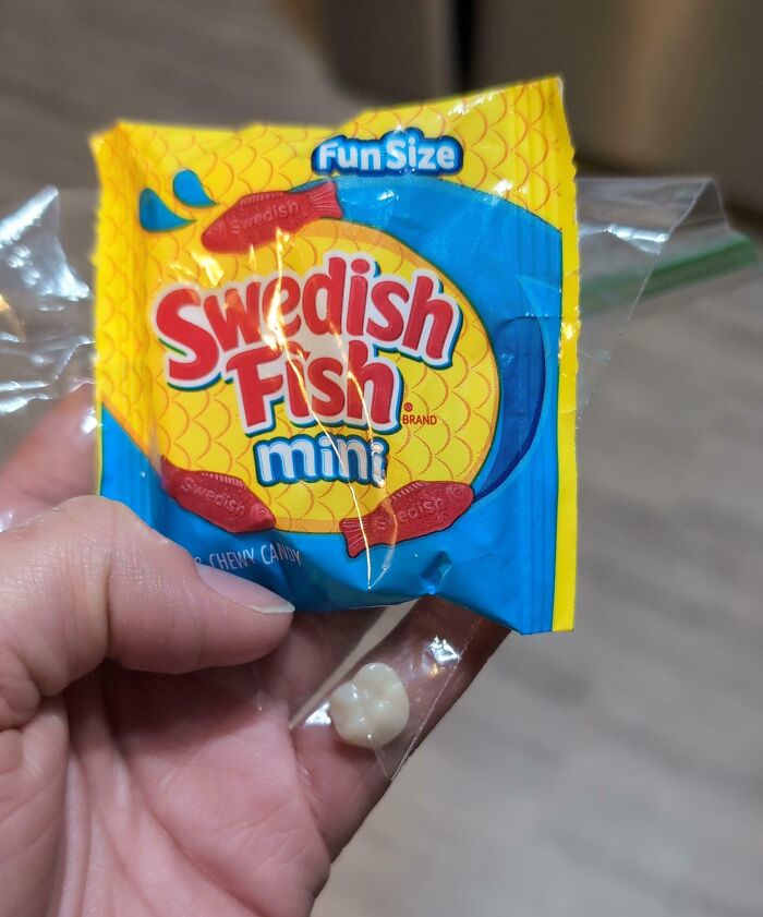 Hand holding a fun size Swedish Fish mini candy package with a single white candy inside, a Halloween fail.