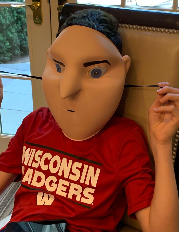 Person wearing oversized Halloween mask and Wisconsin Badgers shirt, displaying a Halloween fail costume idea.
