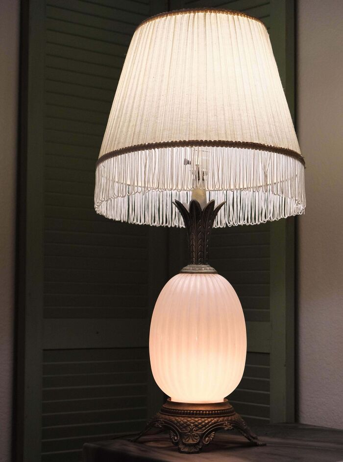 Vintage pineapple table lamp with fringed lampshade glowing warmly, a thrift store jackpot found by lucky shoppers.