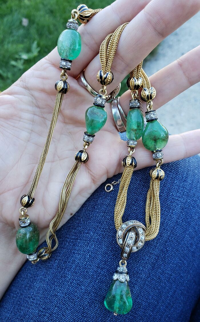 Hand holding vintage green gemstone and gold-tone chain necklace, a lucky thrift store jackpot find for shoppers.