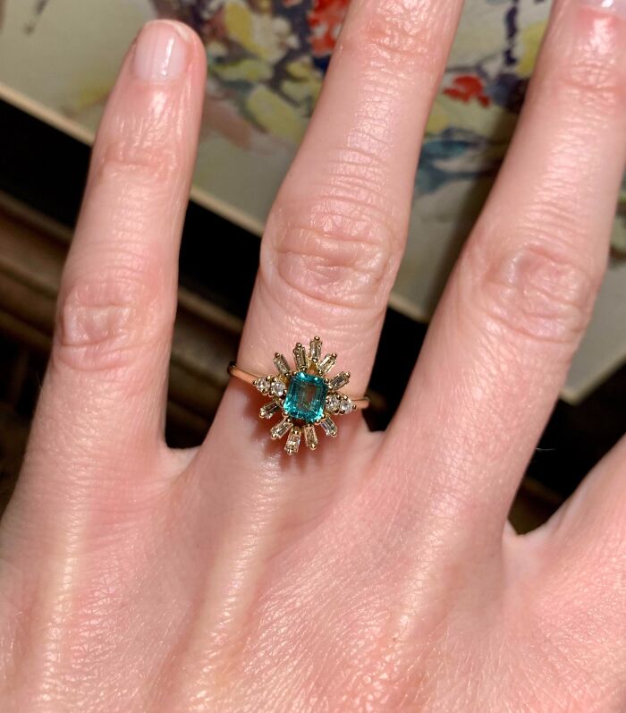 Close-up of a hand wearing a gold ring with a blue stone, showcasing a thrift store jackpot find by a lucky shopper.