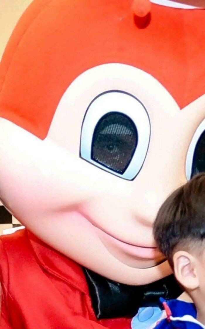 Close-up of a costumed mascot face next to a child, one of the people chuckling at pictures that go hard.