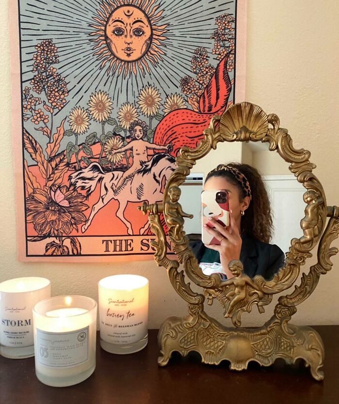 Vintage ornate mirror and thrifting decor with candles and a colorful Sun tarot tapestry on the wall, thrift store jackpot find.