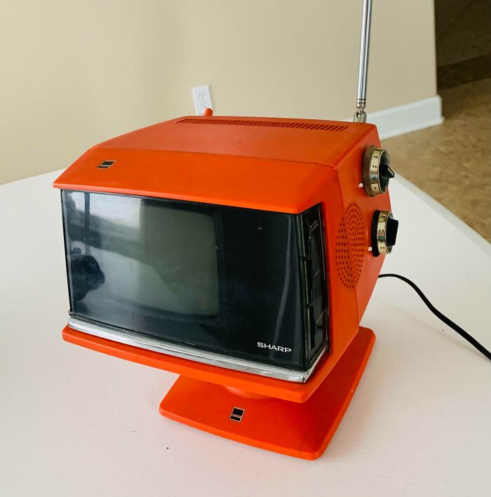 Vintage Sharp red portable television from thrift store jackpot find sitting on white table with dials and antenna.