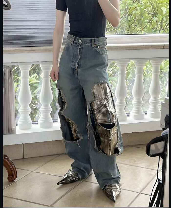 Person wearing edgy ripped jeans with metal armor inserts and pointed metal shoes, showcasing pictures that go hard style.