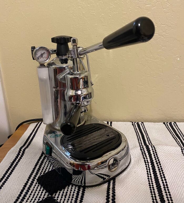 Vintage chrome espresso machine with lever handle on a striped cloth, a thrift store jackpot find for lucky shoppers.