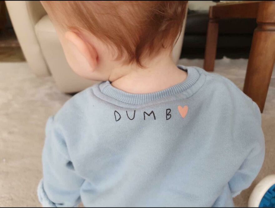Baby wearing a blue shirt with the word dumb written on the back, showing a moment of people knowing what they were doing.