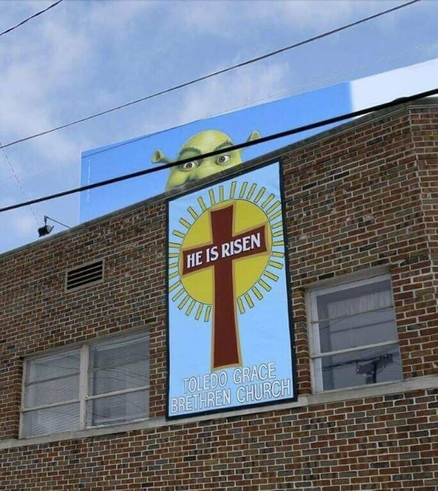 Shrek character peeking over a church building with a religious sign in an urban setting, capturing a bold unexpected moment.