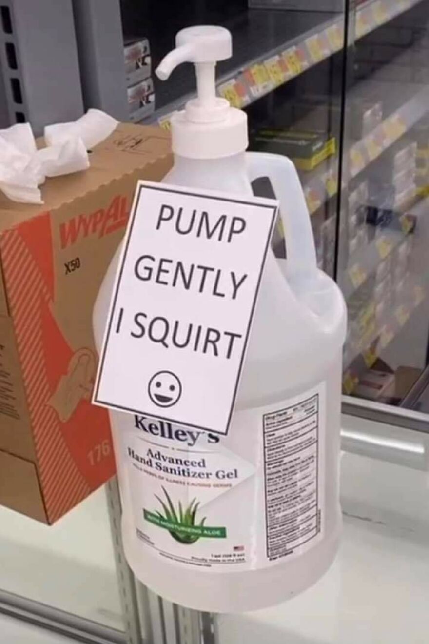 Hand sanitizer bottle with a humorous sign saying pump gently I squirt and a smiling emoji in a store setting.