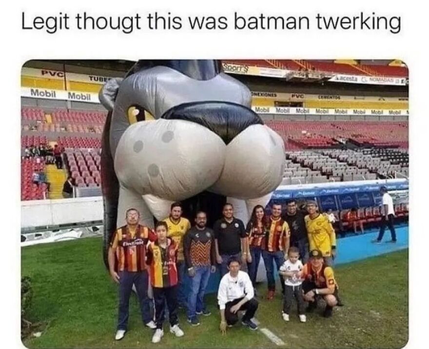 Group of people posing in front of a large inflatable mascot at a stadium, knowing exactly what they were doing.