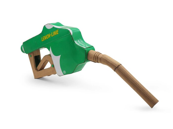 Green and white gas pump nozzle sculpture made from waste materials, showcasing witty commentary on modern life.