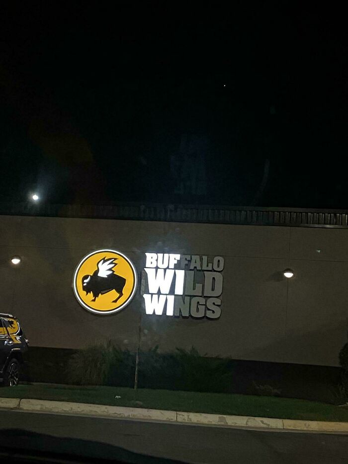 LED sign for Buffalo Wild Wings illuminated on a building exterior at night with a dark sky background.