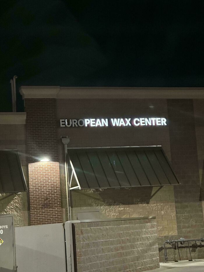 LED sign on building at night showing partial lighting failure with the text European Wax Center glowing unevenly.