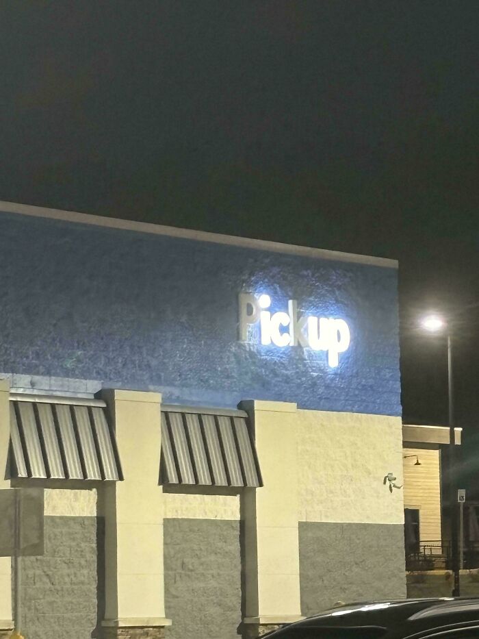 LED sign displaying the word pickup glowing brightly on a building exterior at night under street lighting.