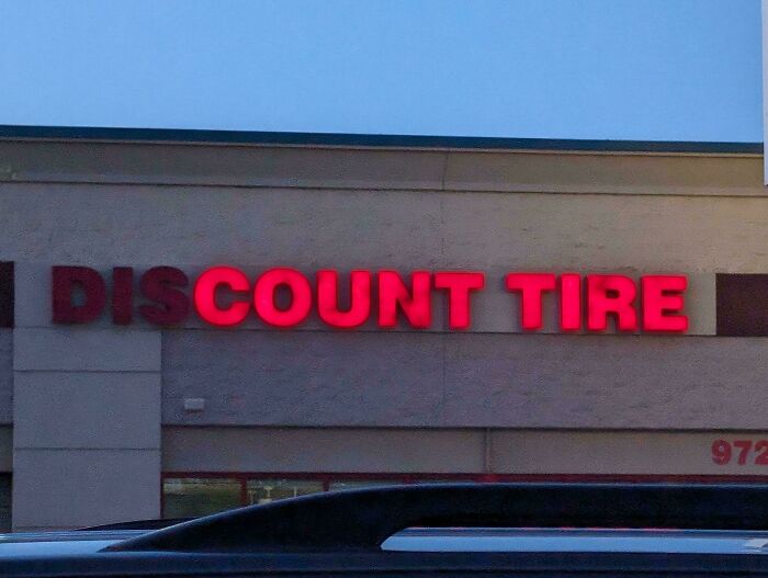 LED signs displaying discount tire in red on the exterior of a commercial building at dusk.