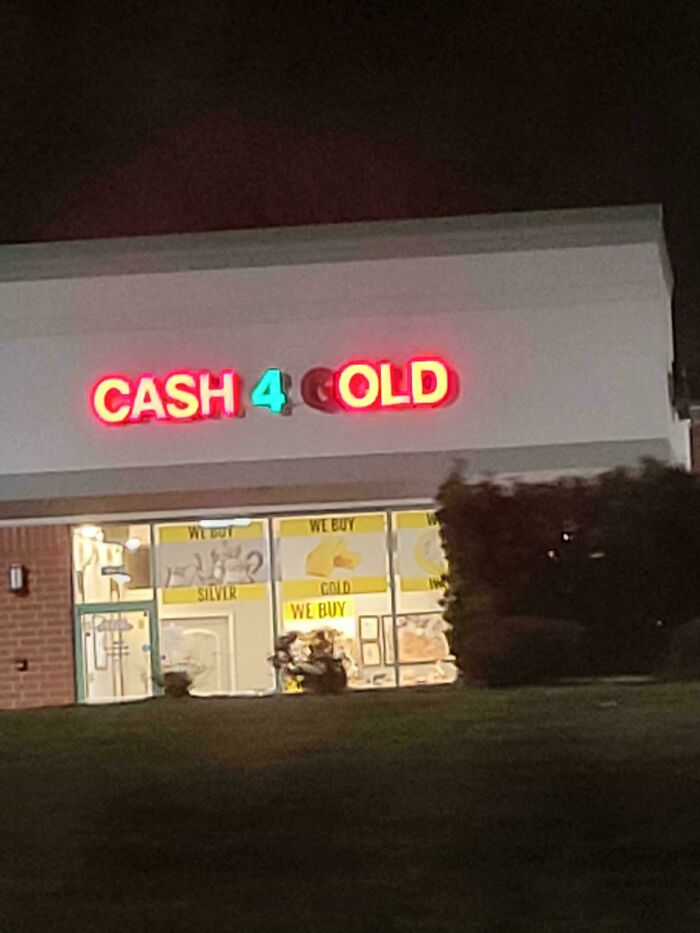 Neon LED sign reading cash 4 gold illuminated on a building facade at night with storefront windows below.