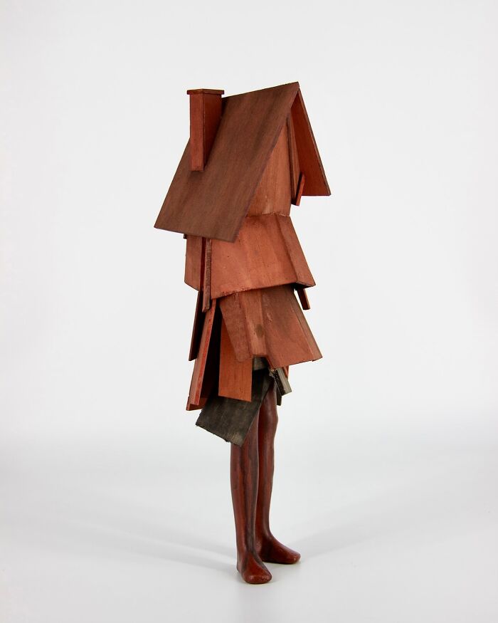 Surreal collage of a walking building with human legs and fragmented collapsing wooden house structure.