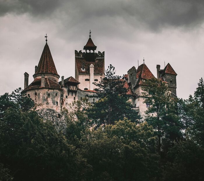 Spooky castle with red rooftops surrounded by dark forest under a gloomy sky, a top spooky destination for Halloween visitors. Spooky castle with red rooftops surrounded by dark forest under a gloomy sky, a top spooky destination for Halloween visitors.