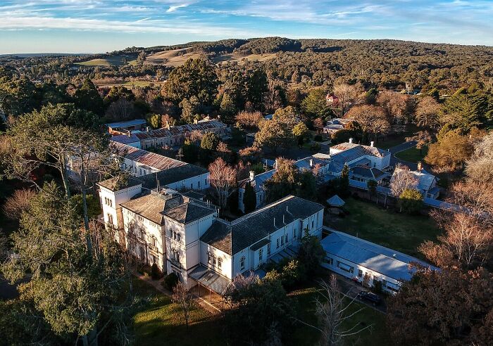 Aerial view of an old, eerie mansion surrounded by dense trees and a gloomy landscape, a spooky destination for Halloween. Aerial view of an old, eerie mansion surrounded by dense trees and a gloomy landscape, a spooky destination for Halloween.