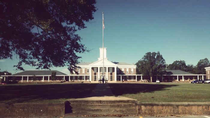 Historic building with tall white columns and flagpole, surrounded by trees, representing spooky destinations for Halloween visits.