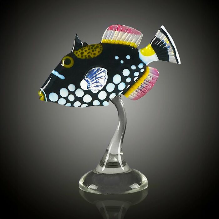 Colorful glass sculpture of a spotted tropical fish mounted on a clear glass stand, showcasing ocean life artistry.