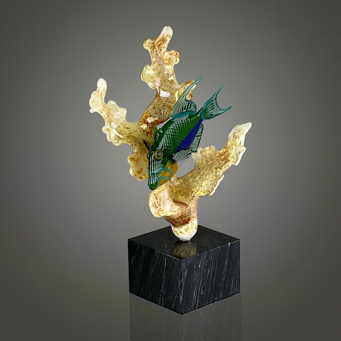 Glass sculpture of a colorful ocean fish swimming around coral, showcasing stunning ocean life glass art on a black base.