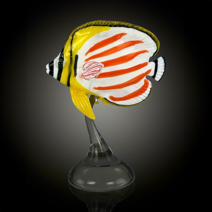 Glass sculpture of a colorful tropical fish showcasing stunning ocean life art on a clear base against a dark background.