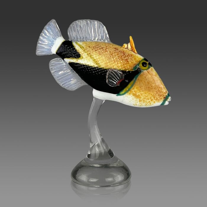 Glass sculpture of a colorful ocean fish displayed on a clear stand, showcasing stunning ocean life artistry.