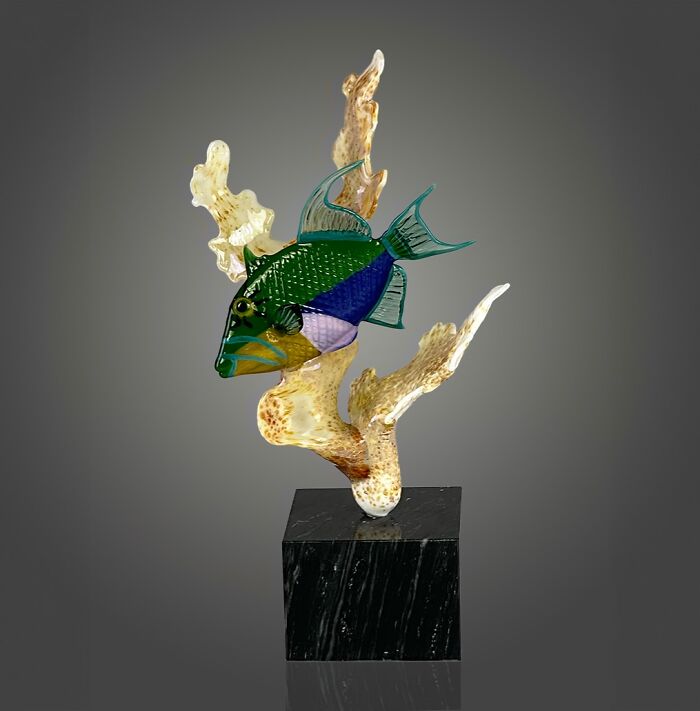 Glass sculpture of a vibrant ocean fish mounted on coral, showcasing stunning glass art and ocean life craftsmanship.