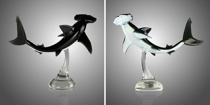 Two stunning glass sculptures of hammerhead sharks, showcasing ocean life in detailed artistic design on clear stands.